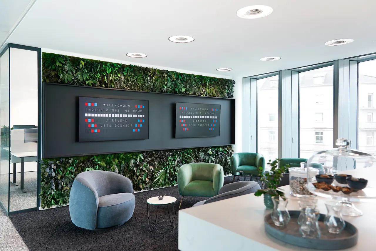 Lounge-Bereich in einem Büro mit begrünter Wand und Sesseln